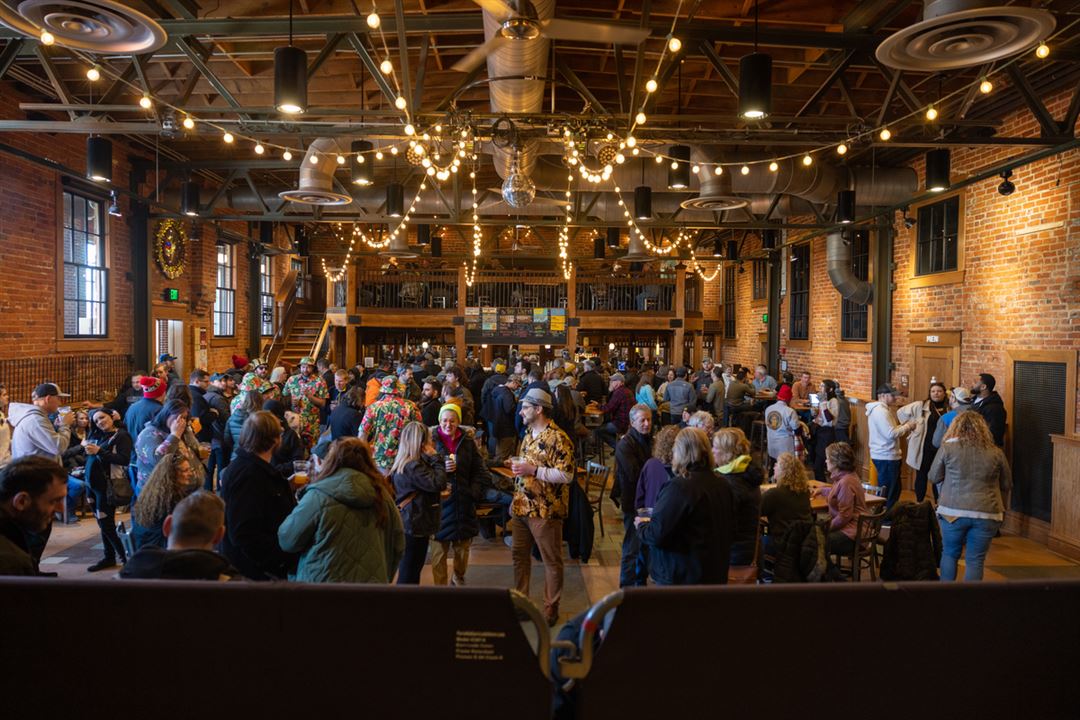 A crowd of people under twinkling lights in a room full of wood
