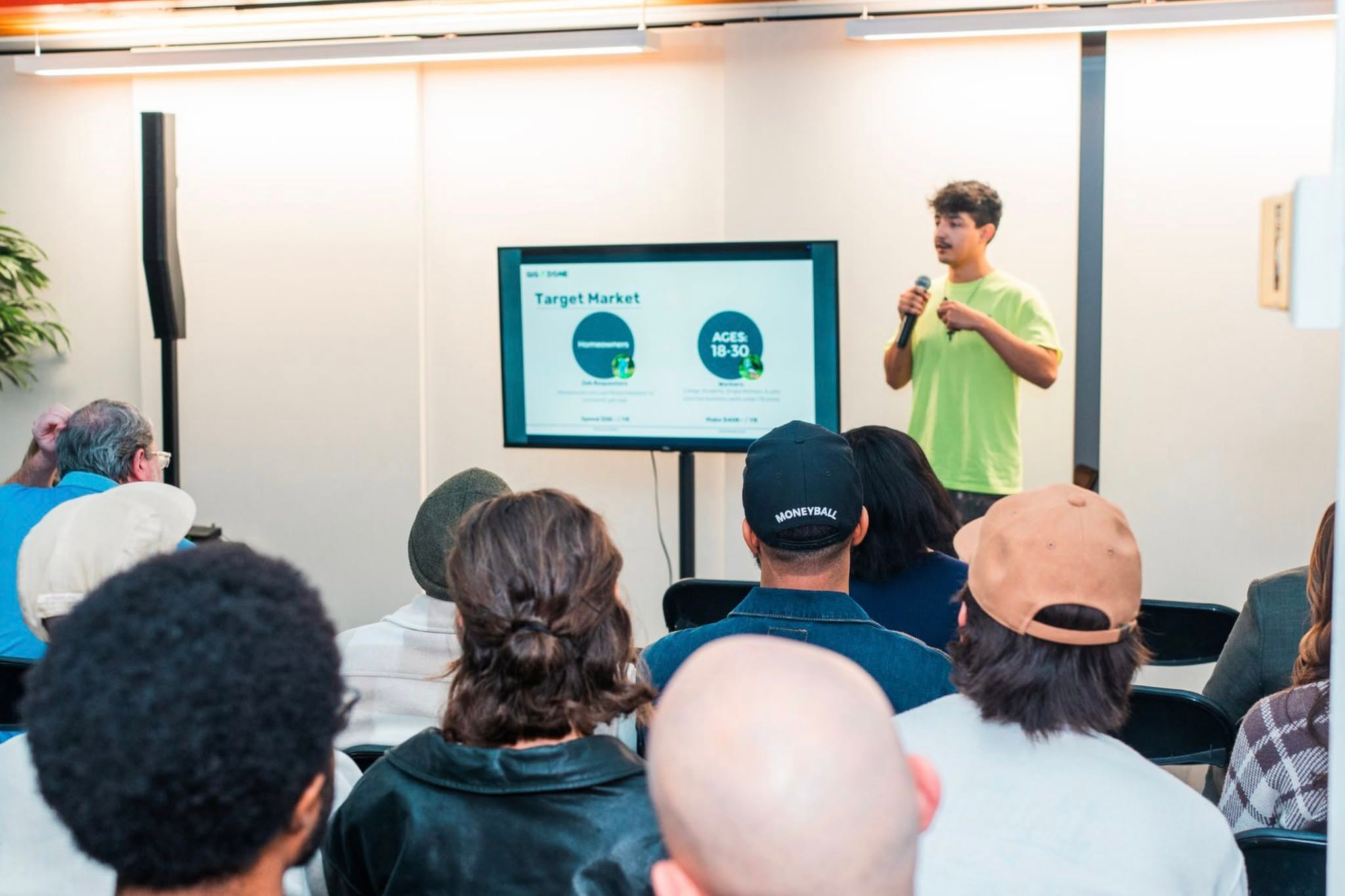 Photo of a man in a green shirt presenting to a group of people