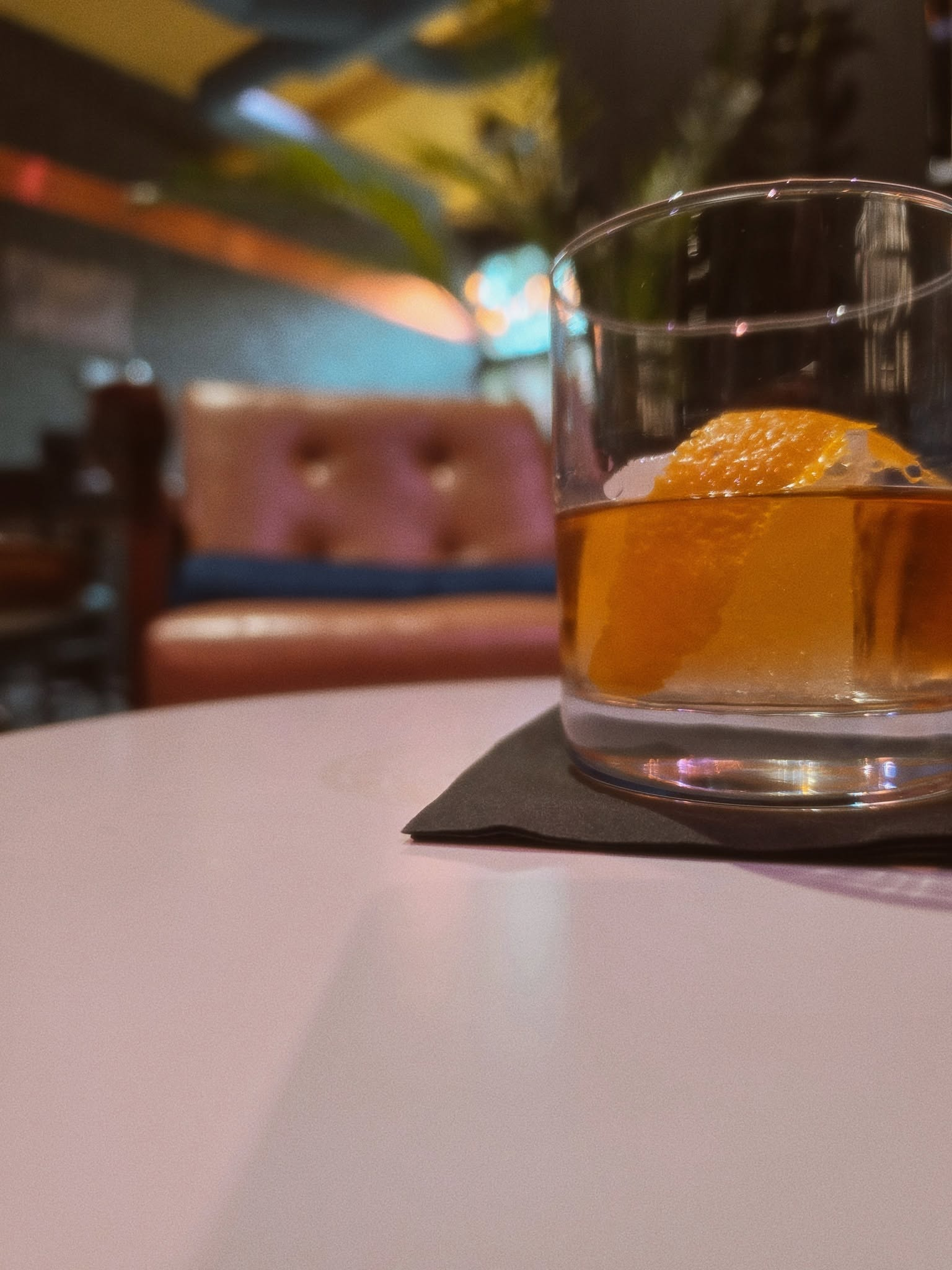 A Negroni cocktail in focus with a sofa in the background